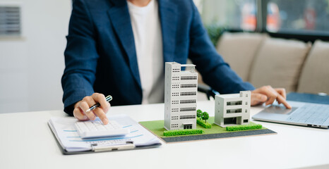 Young real estate agent worker working with laptop and tablet at table in office and small house