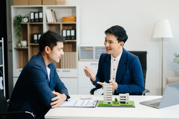 Young real estate agent worker working with laptop and tablet at table in office and small house