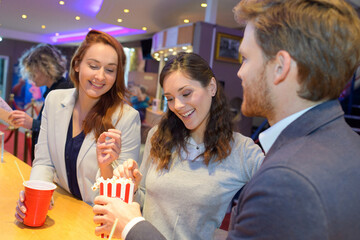 people talking while holding drinks and popcorn