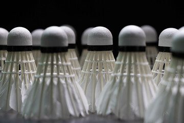  badminton shuttlecocks and badminton rackets are placed on a black background.