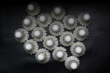  badminton shuttlecocks and badminton rackets are placed on a black background.