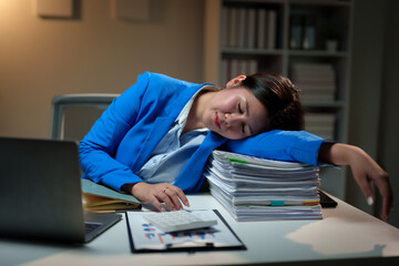 Tired Asian businesswoman Stress from paperwork, headache, sleepiness on piles of documents. Bored from sitting at a desk for a long time and has office syndrome.
