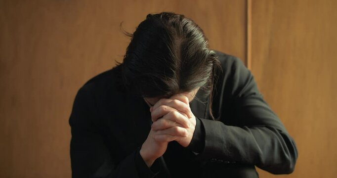 Young man in old church building in front of stained glass window kneeling, praying, worshipping. Christianity, worship, and prayer concept.