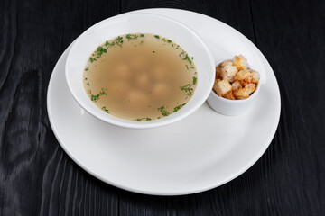 Chicken soup bouillon in a plate with chicken meatballs and croutons