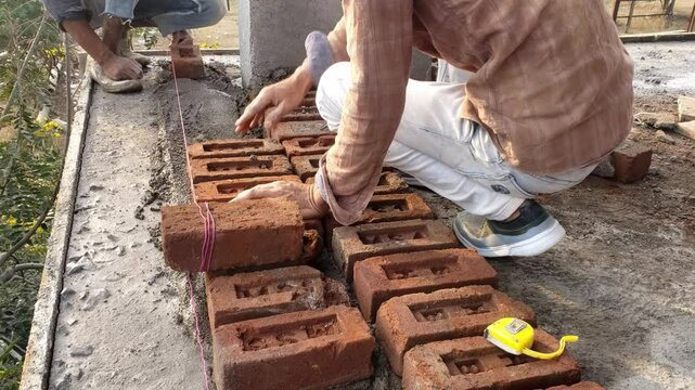 Construction workers constructing brick walls - hard-working concept, manual labor. Two builders laying a brick wall on the construction of a multi-story building.