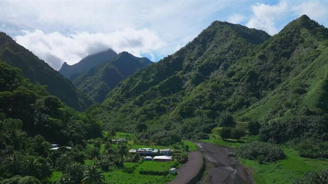 Towering mountain volcano peaks valley rivers Teahupoo town Tahiti French Polynesia Moorea Papeete aerial drone stunning island late morning afternoon blue sky daytime sunny clouds circle right