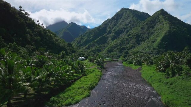 River Valley towering mountain volcano peaks Teahupoo town Tahiti French Polynesia Moorea Papeete aerial drone stunning island late morning afternoon blue sky daytime sunny clouds forward pan up