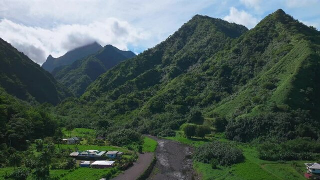 Towering mountain volcano peaks valley rivers Teahupoo town Tahiti French Polynesia Moorea Papeete aerial drone stunning island late morning afternoon blue sky daytime sunny clouds backward pan up