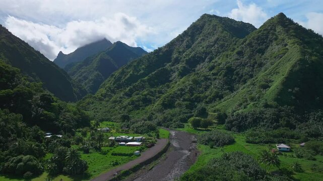 Towering mountain volcano peaks valley rivers Teahupoo town Tahiti French Polynesia Moorea Papeete aerial drone stunning island late morning afternoon blue sky daytime sunny clouds forward pan up