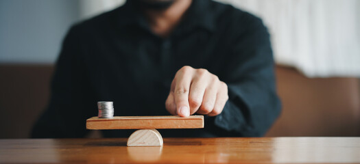 Businessperson Balancing Stacked Coins On Seesaw
