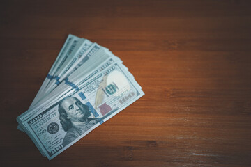 many hundred dollar bills on wooden table
