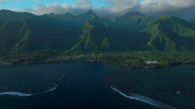 Perfect golden hour sunset towering mountain peaks surf reef break channel Teahupoo Wave Tahiti French Polynesia aerial drone view incredible island landscape Moorea Bora Bora Papeete backwards pan
