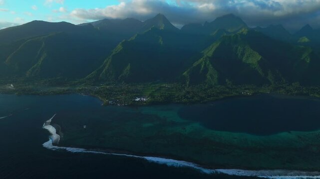 Golden hour sunset towering mountain peaks surf reef break channel Teahupoo Wave Tahiti French Polynesia aerial drone incredible island landscape clouds Olympics Moorea Bora Bora Papeete circle right