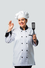 Young Indian asian female chef smiling with spatula - professional culinary expert