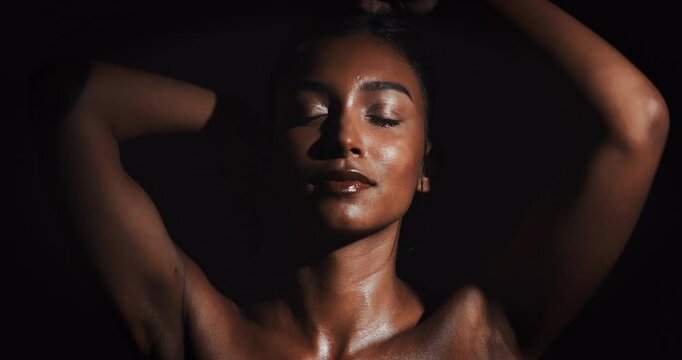 Woman, sensual and glow for skincare with beauty, natural shine and erotic confidence in dark studio. Girl, dermatology and body with skin shimmer, sexuality and sexy movement by black background