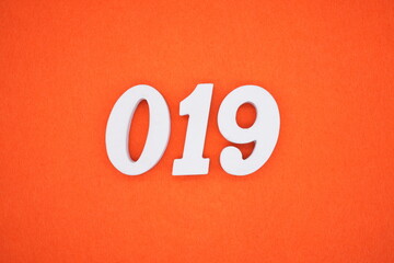 The numbers are made of white painted wood. Placed on the floor was orange paper.
