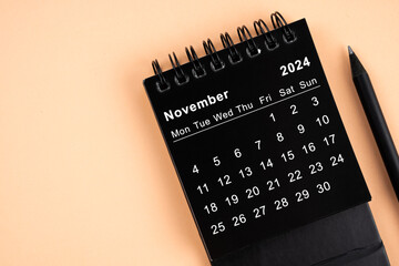 November 2024 Black spiral desktop calendar and wooden pencil