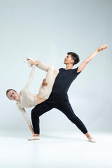 Ballet Dance Concepts. Sportive Couple of Asian Man and Caucasian Woman Performing As Ballet Dancers On Grey in Studio During Suppots © danmorgan12