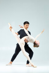 Ballet Concepts. Sensual Passionate Professional International Sportive Couple of Asian Man and Caucasian Woman Performing As Ballet Dancers On Grey in Studio During Suppots As Classical Dance © danmorgan12