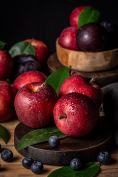 Top view of apples, plums and blueberries with green leaves