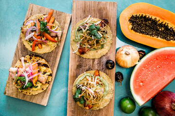 Tacos with colorful toppings and fresh produce on wooden boards.