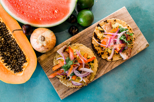 Colorful tacos and fresh produce on a wooden board.