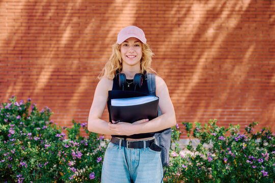 University student holding books and looking at camera