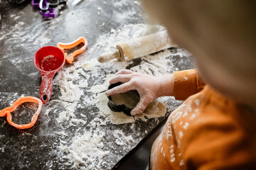 Child shaping Halloween cookies wth cookie cutters at home