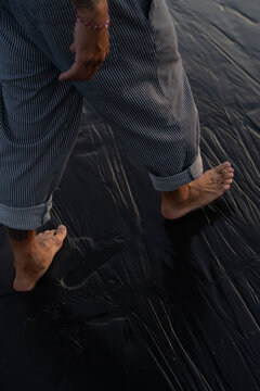Man walks along the beach, bare feet on the sand.