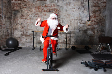 A man dressed as Santa Claus trains on an exercise bike in the gym.