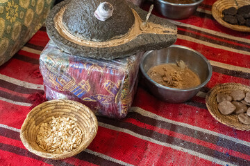 Traditional argan oil production setup, stone grinder, argan seeds, woven baskets, metal bowls, brown paste