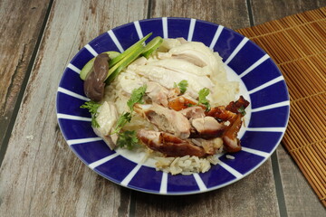 Steamed and grilled chicken thigh topping on cooked jasmine rice serving on the plate. Famous fast food menu in Asia. 
