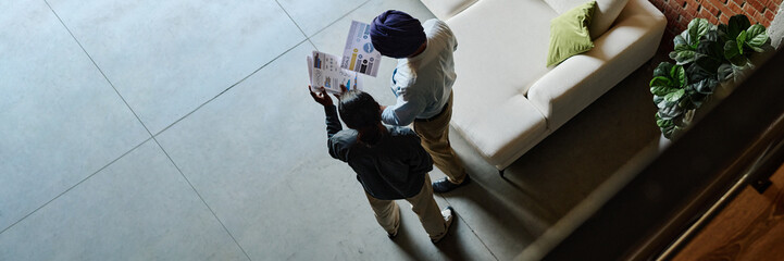 Website header shot of two office colleagues holding financial report and discussing documents in office lobby top view