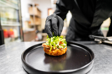 A chef in a professional kitchen meticulously garnishes a gourmet dish, emphasizing culinary...