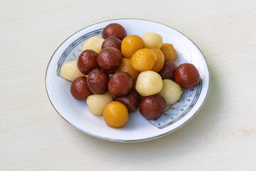 Delicious and juicy Bangladeshi sweets on a white plate on light wooden background. It is called Baby sweet because little in size.