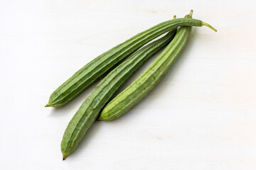 Fresh ridge gourds placed on a light wooden surface. It is also known as Chinese okra, Jhinga, Silk...