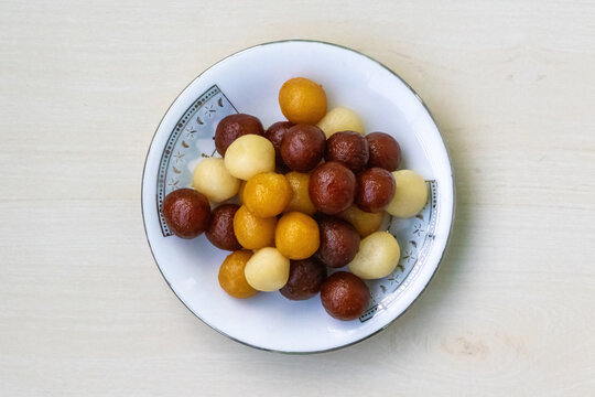 Delicious Bangladeshi sweets on a white plate on light wooden background. It is called Baby sweet because little in size. Very juicy and tasty sweet.