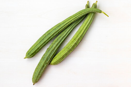 Fresh ridge gourds placed on a light wooden surface. It is also known as Jhinga, Chinese okra, Silk squash, and Turai.