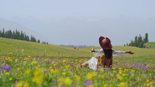 Young woman traveler relaxing and enjoying beautiful Scenery landscape with colorful flowers in Kalajun grassland of Xinjiang in summer