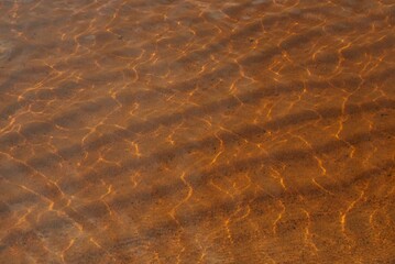 Clear lake water and sand at the bottom. Waves of sand at the bottom of the lake.