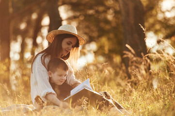 Reading the book. Mother and son are in the forest together