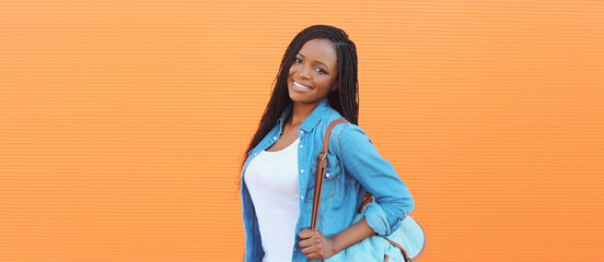 Portrait of happy stylish young african woman in casual clothing, glasses posing in the city