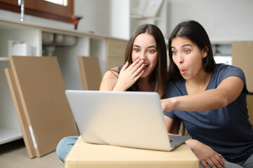 Amazed roommates checking laptop reforming house