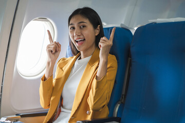 Smiling Asian woman enjoying her comfortable flight while sitting in the airplane cabin