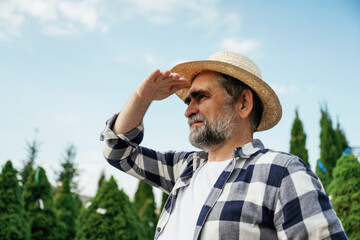 Looking to the side, far away. Senior gardener is at work at daytime