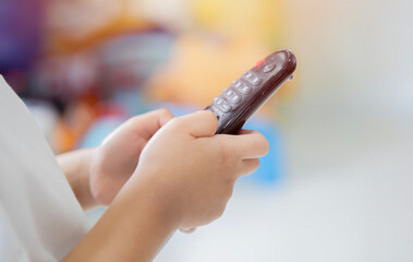 Obraz premium Close-up side view of a kid using television remote control.
