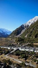 Scenic view of a suspension bridge over a river with snow-capped mountains in the background