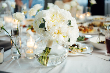 An incredibly beautiful wedding bouquet lies on the table during dinner.