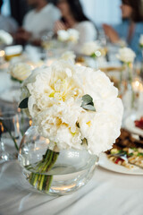 An incredibly beautiful wedding bouquet lies on the table during dinner.