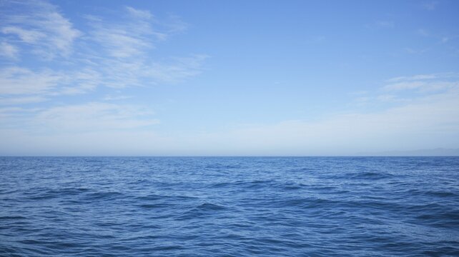 Serene view of the ocean under a clear blue sky with scattered clouds in New Zealand
